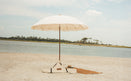 Luxury beige beach umbrella on a sandy beach with water and sky in the background
