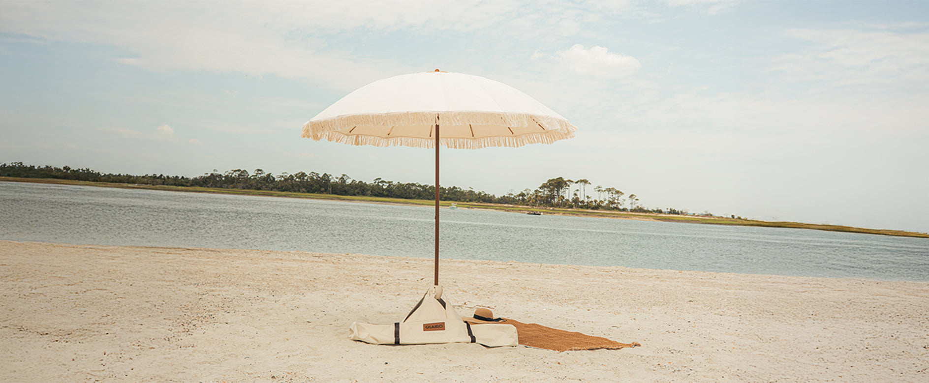 Luxury beige beach umbrella on a sandy beach with water and sky in the background