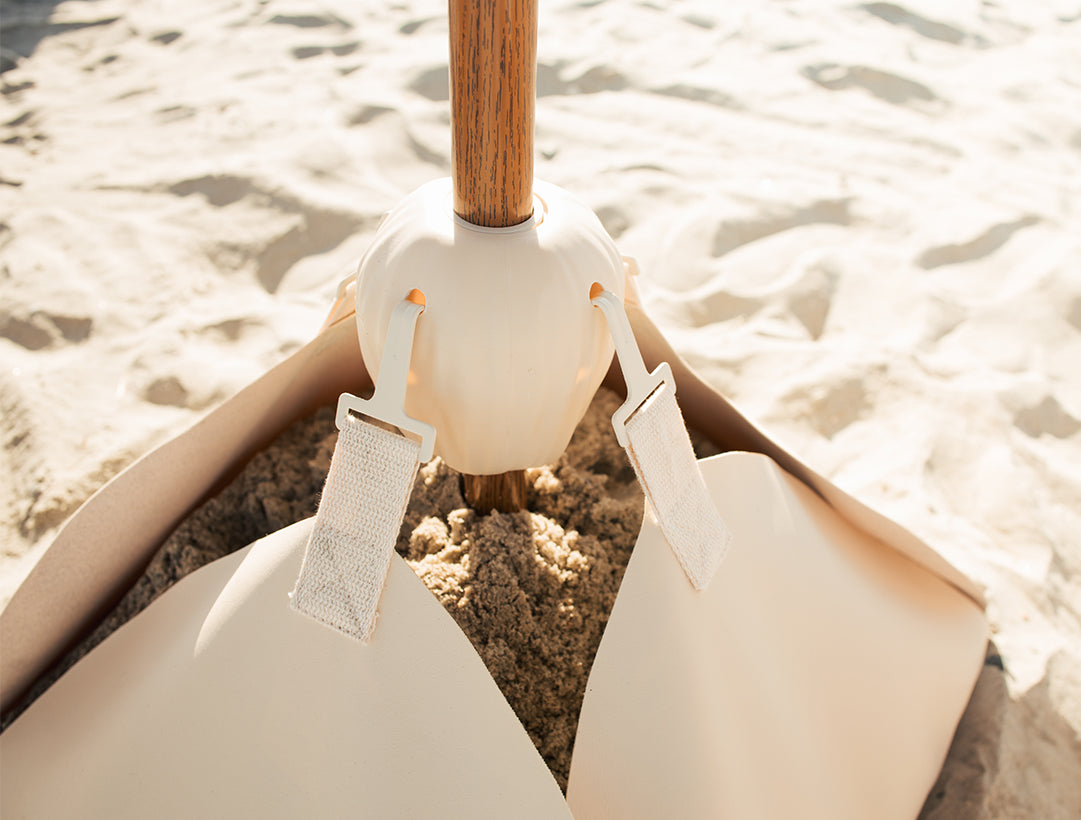 Natural Inspired beige umbrella base (the blossom base) filled with 100lbs of sand and the conch connector.