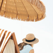 Women wearing a straw hat under a Natural umbrella on a beach.