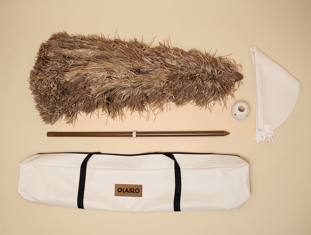 The Sirocco Beach umbrella and all included parts: The dried grass Canopy, The canvas carry bag, the conch connector, the blossom base, and the aged bamboo pole