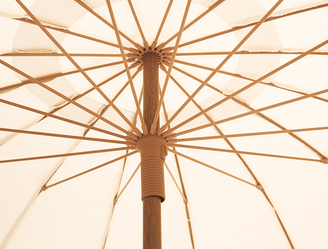 Close-up of a beige umbrella with aged bamboo pole and ribs.