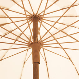 Close-up of a beige umbrella with aged bamboo pole and ribs.