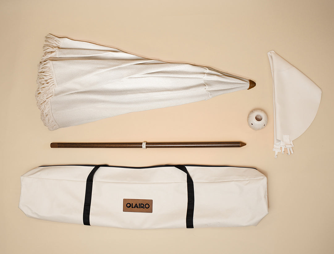 Beige umbrella with all the included parts; Canopy, Canvas Carry bag, Conch connector, blossom base, and pole