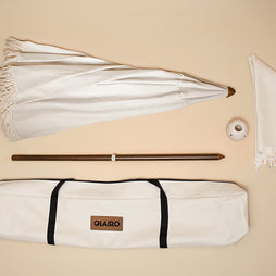 Beige umbrella with all the included parts; Canopy, Canvas Carry bag, Conch connector, blossom base, and pole