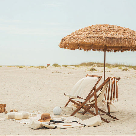 The sirocco a natural beach umbrella, wooden chair, and a luxury beach set-up. In the distance is the Calima beach Umbrella